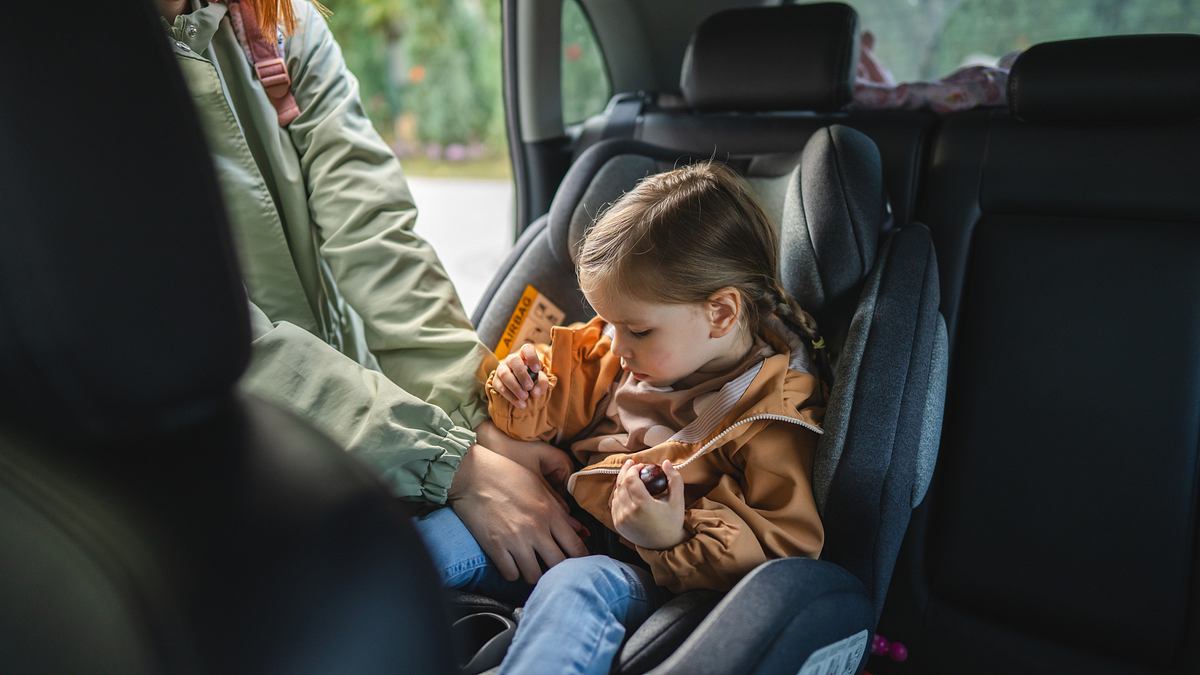 Kind im Kindersitz wird von weiblicher Person angeschnallt (Themenbild)