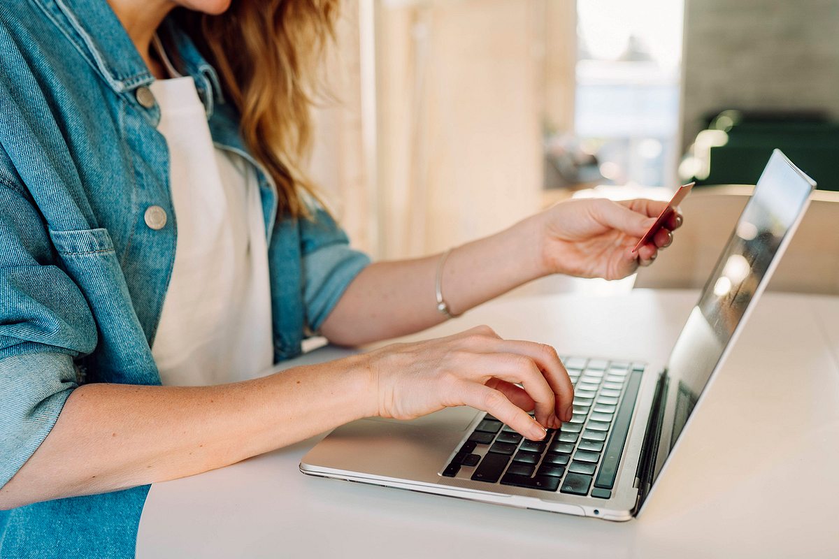 Frau beim Onlineshopping hält eine Kreditkarte in der Hand.