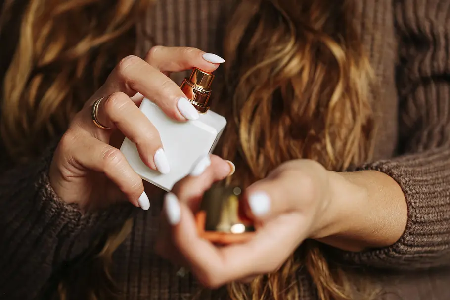 Parfum-Trends 2026 Nahaufnahme von Frauenhänden, die sich ein weißes Parfum aufs Handgelenk sprüht