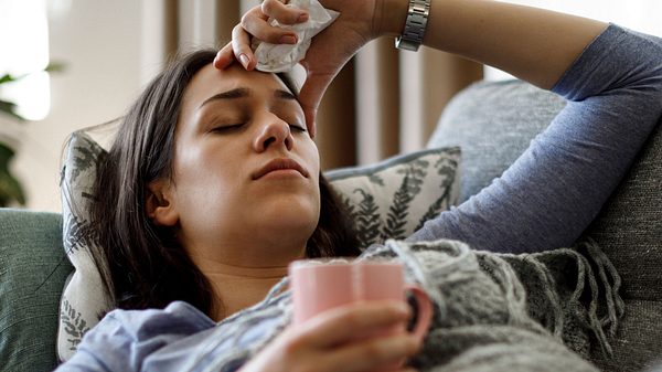 Frau liegt mit Grippesymptomen auf dem Sofa - Foto: damircudic / iStock