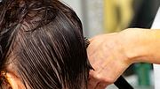 Einer dunkelhaarigen Frau wird das nasse Haar geschnitten.  - Foto: Anton Vakhrushev/iStock (Themenbild)