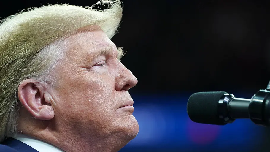 Donald Trump vor Mikrofon Donald Trump im Profil vor einem Mikrofon bei einer politischen Veranstaltung.