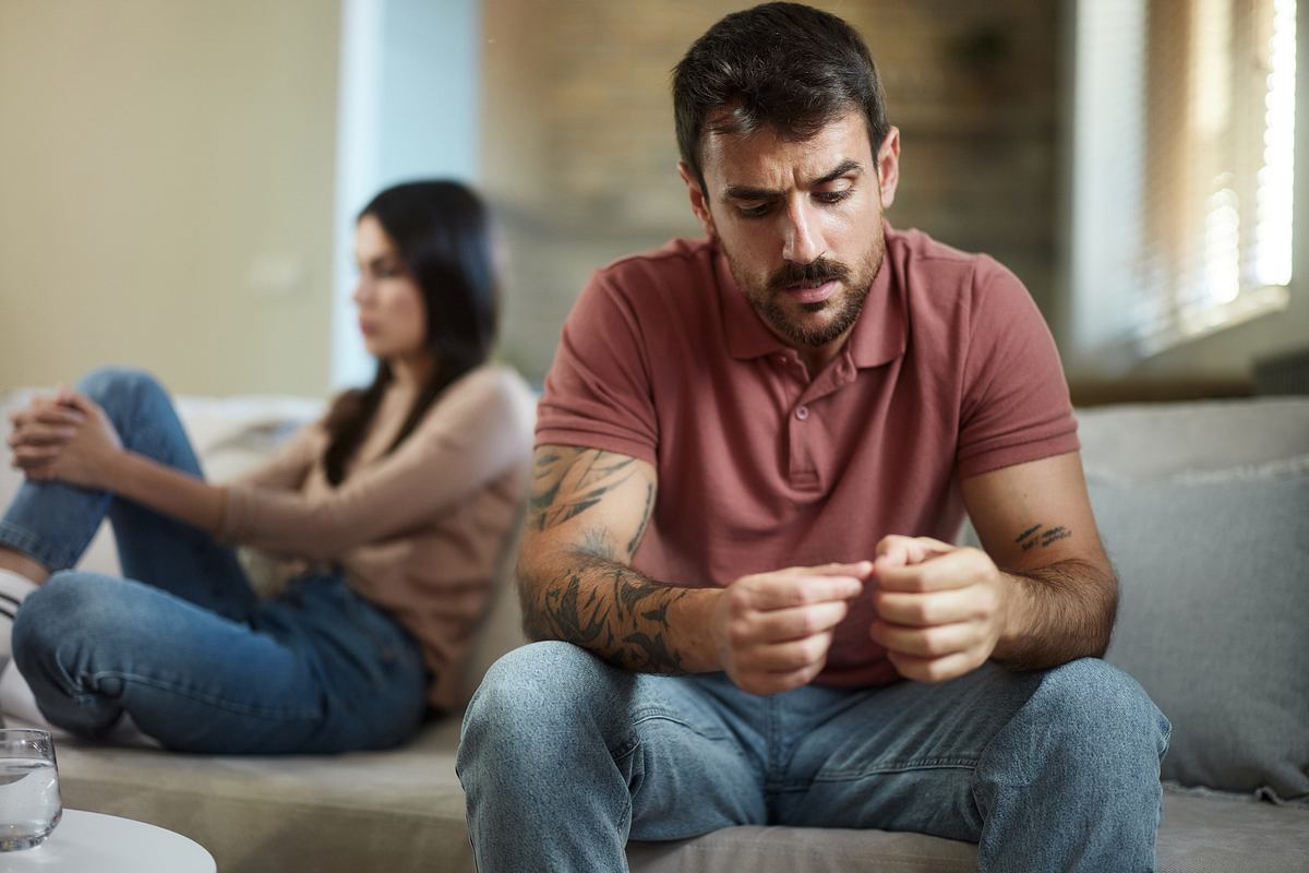 Ein Paar sitzt distanziert auf der Couch (Themenbild)