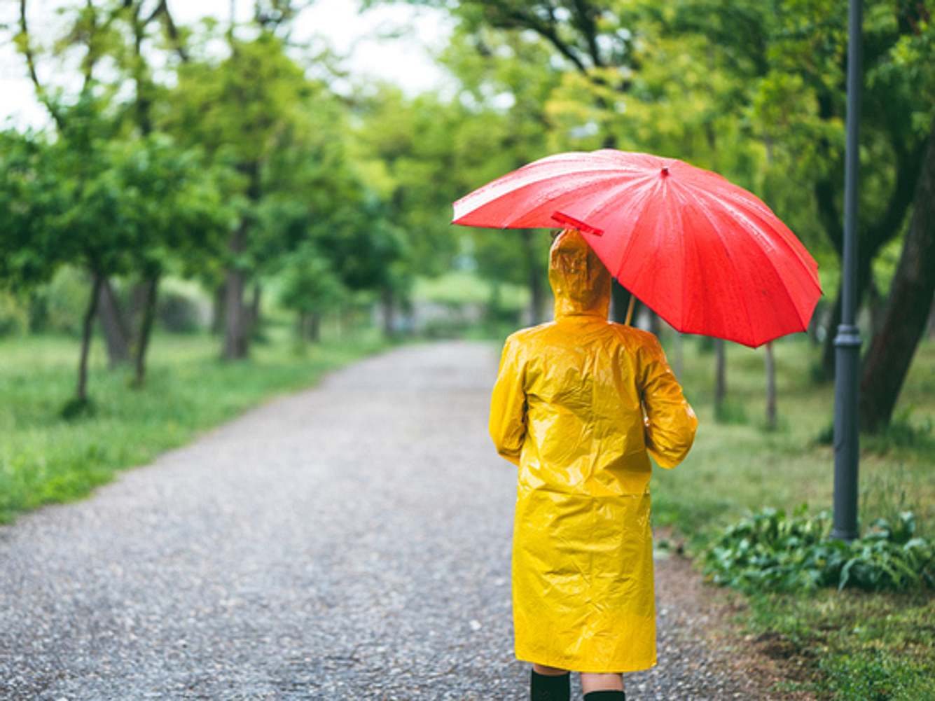 Frau mit wasserdichtem Regenmantel und Regenschirm