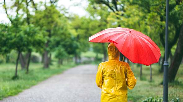 Frau mit wasserdichtem Regenmantel und Regenschirm - Foto: iStock/urbazon
