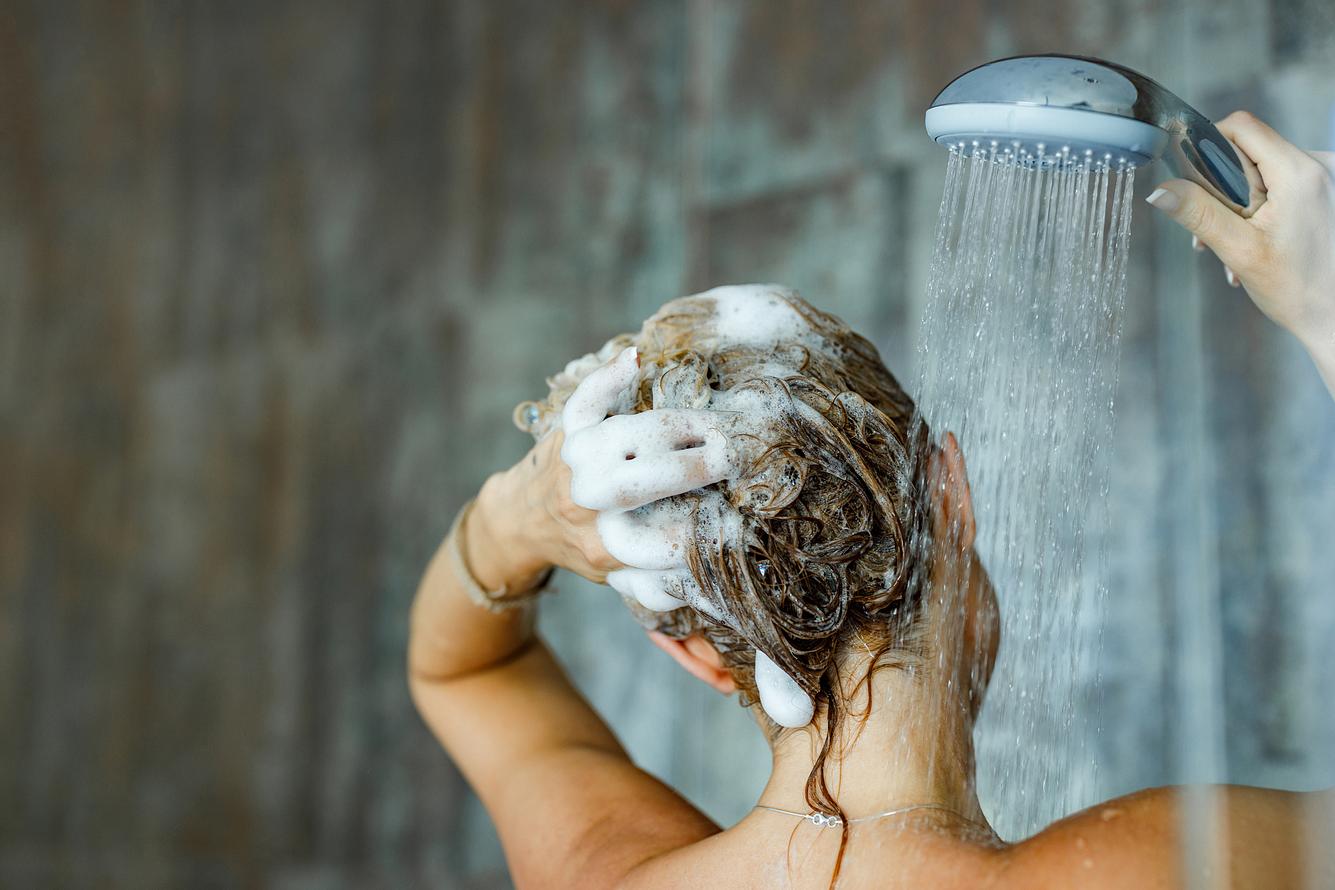 Frau wäscht Haar mit Reinigungsshampoo