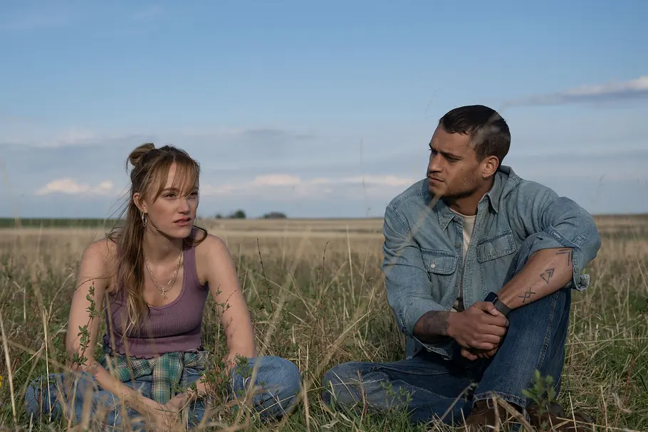 Kenna (Maika Monroe) und Ledger (Tyriq Withers) in „Reminders of Him“ sitzen auf einem Feld und unterhalten sich.