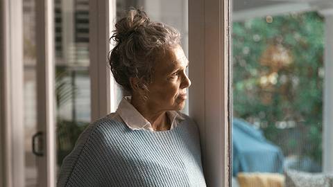 Rente mit 70: Frau schaut gedankenveloren aus dem Fenster - Foto: iStock / Anna Frank