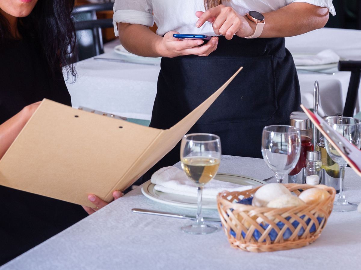 Paar bestellt mit gastfreundlicher Kellnerin im Restaurant.