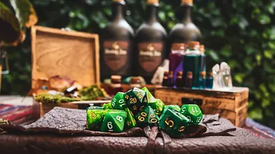 RPG-Würfel auf einem Tisch, dahinter eine Holzkiste - Foto: iStock/Esther Derksen