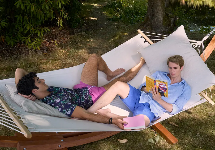 Taylor Zakhar Perez als Alex und Nicholas Galitzine als Henry lesen in einer Hängematte im ersten Teil von „Royal Blue“.