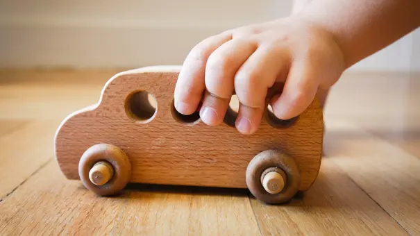 Kind spielen mit Holz-Spielzeug-Bus auf Holzfußboden - Foto: iStock/artedetimo