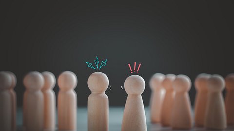 Symbolbild Konflikt- oder Meinungsverschiedenheitskonzept. Hölzerne Spielfiguren, die sich streiten - Foto: KTStock/iStock