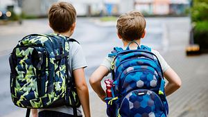 Zwei Jungs mit Schulranzen laufen eine Straße entlang (Themenbild) - Foto: romrodinka/iStock