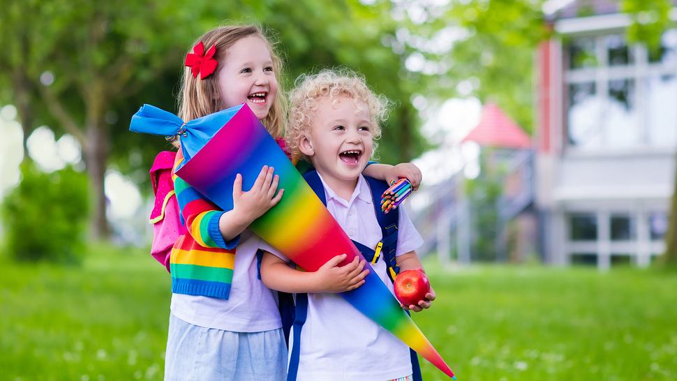 Kinder mit Regenbogenschultüte, Apfel und Stiften (Themenbild) - Foto: FamVeld/iStock (Themenbild)