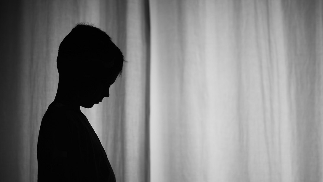 Trauriger Junge allein vor einem Vorhang - Foto: kieferpix/iStock