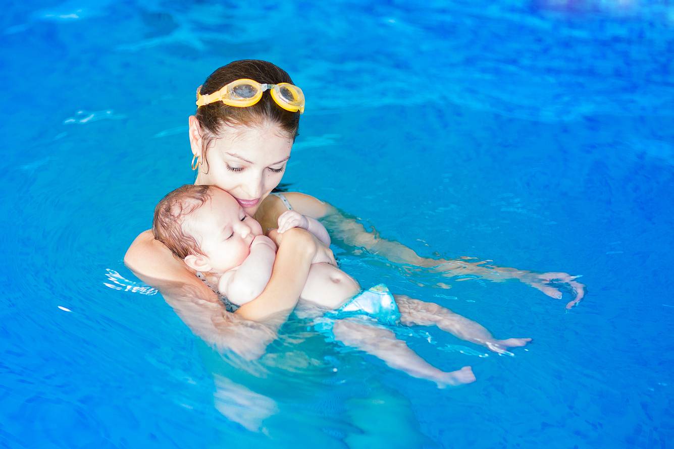 Baby in Schwimmwindeln mit Mutter zusammen beim Babyschwimmen