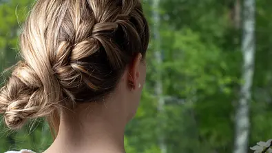 Frau mit seitlichem, geflochtenen Dutt steckt mit dem Rücken zur Kamera. - Foto: erikreis/iStock (Themenbild)