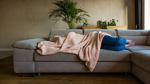 Kühlende Decken gegen die Hitze: Frau liegt auf dem Sofa - Foto: iStock/ izusek 