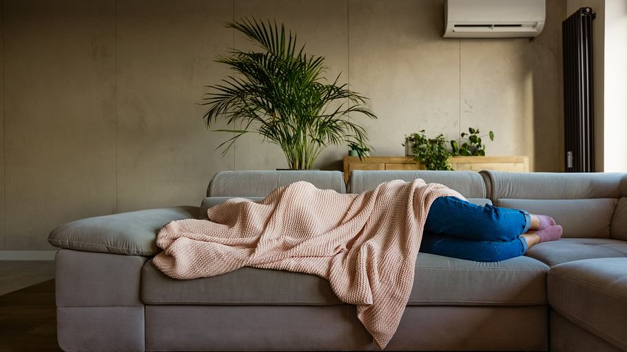 Kühlende Decken gegen die Hitze: Frau liegt auf dem Sofa