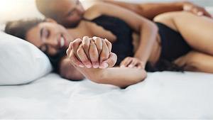 Pärchen liegt kuschelnd in Löffelchenstellung im Bett und hält sich an der Hand - Foto: Jacob Wackerhausen / iStock