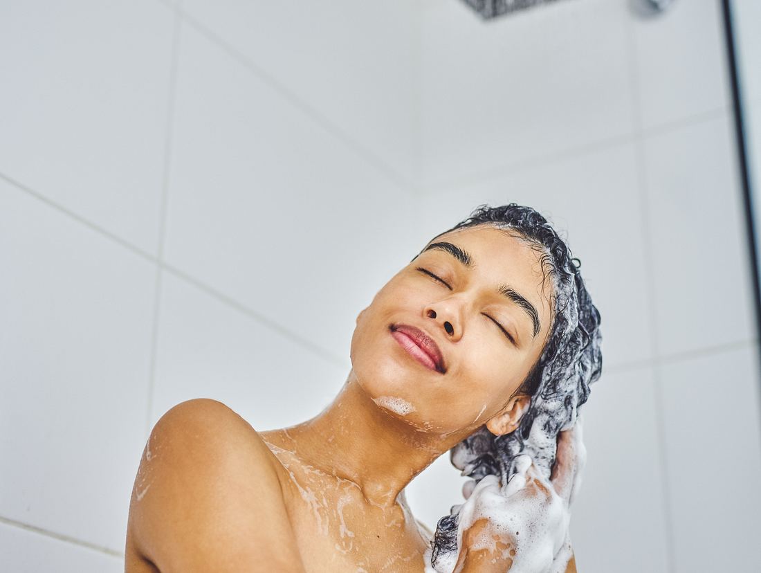 Frau wäscht Haare mit Shampoo ohne Mikroplastik