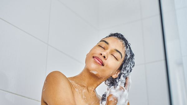 Frau wäscht Haare mit Shampoo ohne Mikroplastik - Foto: iStock/Moyo Studio