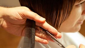 Das kurze Haar einer Frau wird mit einer Schere geschnitten. - Foto: AleksandarNakic/iStock (Themenbild)