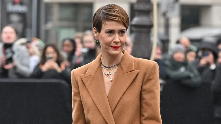 Sarah Paulson mit braunem Blazer und mehreren Ketten, trägt roten Lippenstift und einen kurzen Side-Cut