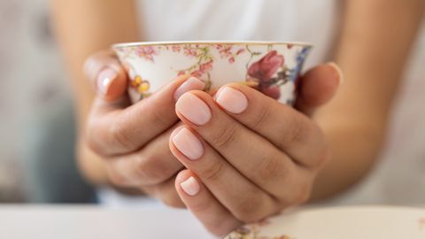 Eine Frau hält eine Porzellantasse in den Händen - Foto:  miodrag ignjatovic/iStock