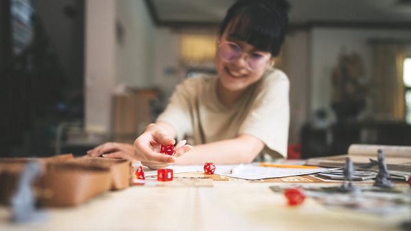 Frau spielt alleine ein Brettspiel und würfelt (Themenbild) - Foto: Wiphop Sathawirawong/iStock