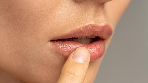 Frau fasst sich mit dem rechten Zeigefinger an die leicht geöffneten Lippen (Themenbild) - Foto: Dima Berlin/iStock