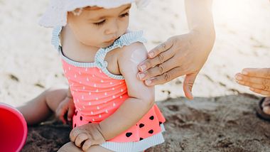 hand cremt baby am arm mit sonnencreme ein - Foto: iStock / ozgurcankaya