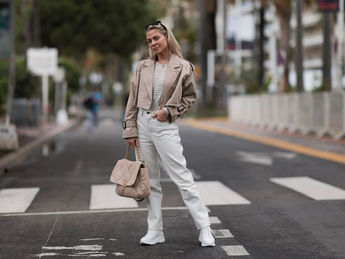 Sportlich-eleganter Look mit weißen Jeans und weißen Sneakern, kombiniert mit einer beigen Lederjacke. 