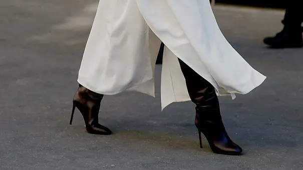 Stiefel-Trends 2026: Frau auf der Straße mit schwarzen Stiefeln und einem weißen Trenchcoat - Foto: ddp/abaca press Stiefel-Trends 2026: Frau auf der Straße mit schwarzen Stiefeln und einem weißen Trenchcoat - Foto: ddp/abaca press
