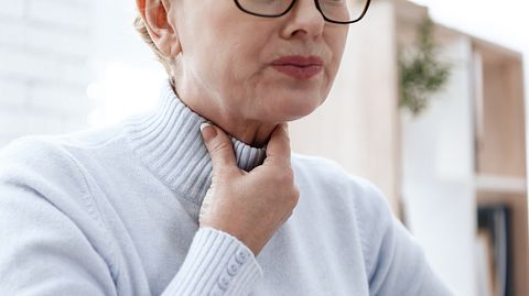 Frau hält sich den Hals und presst die Lippen zusammen (Themenbild) - Foto: T Turovska/iStock