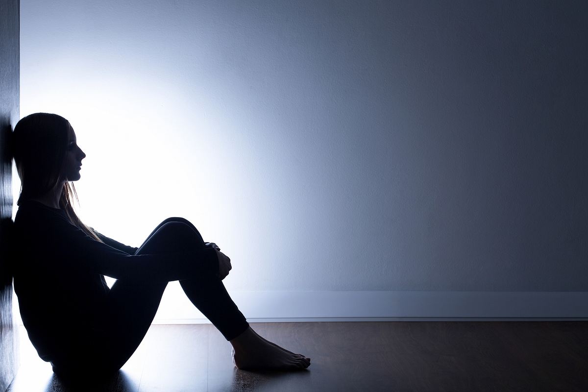 Teenager sitzt traurig auf dem Fußboden.
