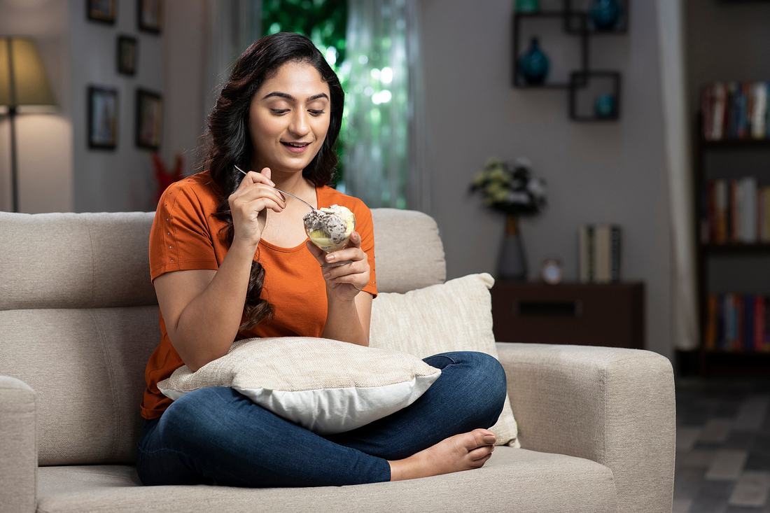Frau isst Eis auf der Couch