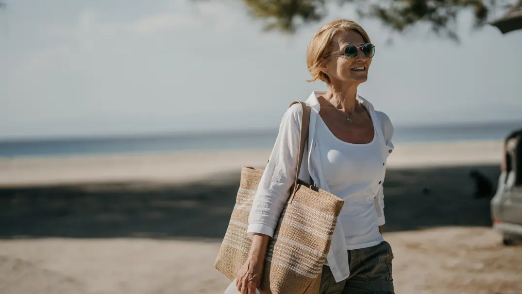 Frau in weißer Bluse geht am Strand.  - Foto: iStock/freemixer