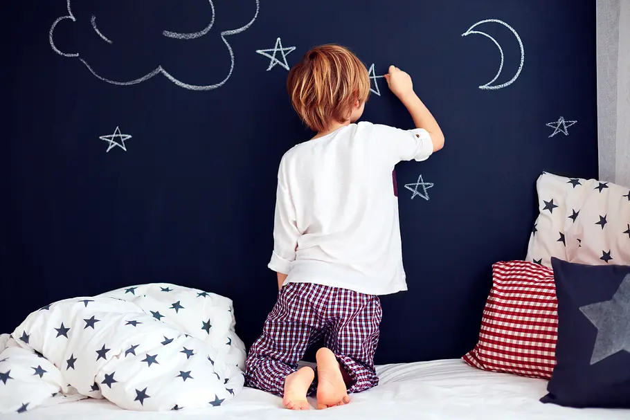 tafelfarbe Kind malt mit Kreide auf einer Wand mit Tafelfarbe