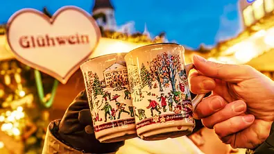 Zwei Glühweintassen auf dem Weihnachtsmarkt werden miteinander angestoßen - Foto: IMAGO / Wolfgang Maria Weber