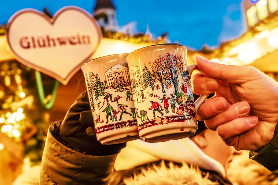 Tassen auf dem Weihnachtsmarkt Zwei Glühweintassen auf dem Weihnachtsmarkt werden miteinander angestoßen