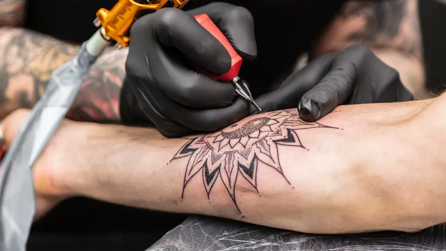 Tattoo gegen Vorstellungsgespräch Ein Mann bekommt ein schwarzweiß Tattoo auf den rechten Unterarm gestochen.