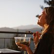 Frau sitzt mit Essen auf dem Balkon und genießt die Ruhe - Foto: AscentXmedia/iStock