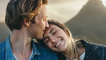Mann küsst Frau auf die Stirn, sie lächelt und lehnt sich an ihn (Themenbild) - Foto: Timm Creative/iStock Mann küsst Frau auf die Stirn, sie lächelt und lehnt sich an ihn (Themenbild) - Foto: Timm Creative/iStock