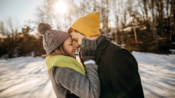 Verliebtes Paar im sonnigen Winter mit Mützen im Schnee (Themenbild) - Foto: eclipse_images/iStock