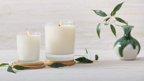 Vegane Kerzen in Weiß neben Vase - Foto: iStock/Maya23K