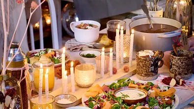 Festlich dekorierter Tisch mit Kerzen und verschiedenen Gerichten. - Foto: Bauer Media Group