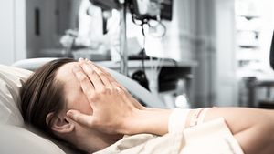 Frau liegt im Kreißsaal und verdeckt ihr Gesicht mit den Händen. - Foto: kieferpix / iStock