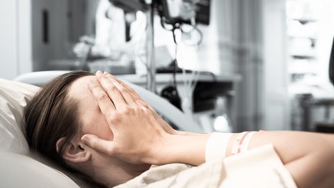Frau liegt im Kreißsaal und verdeckt ihr Gesicht mit den Händen. - Foto: kieferpix / iStock